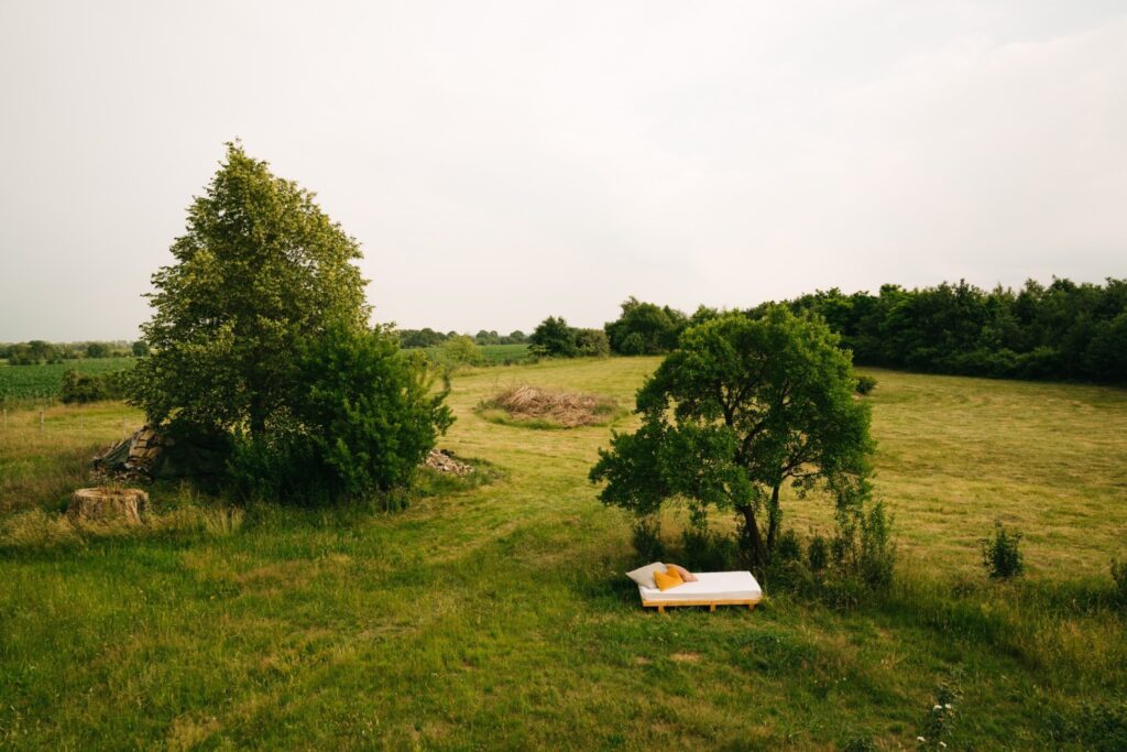 Weißbezogenes Bett auf einem großen grünen Grundstück