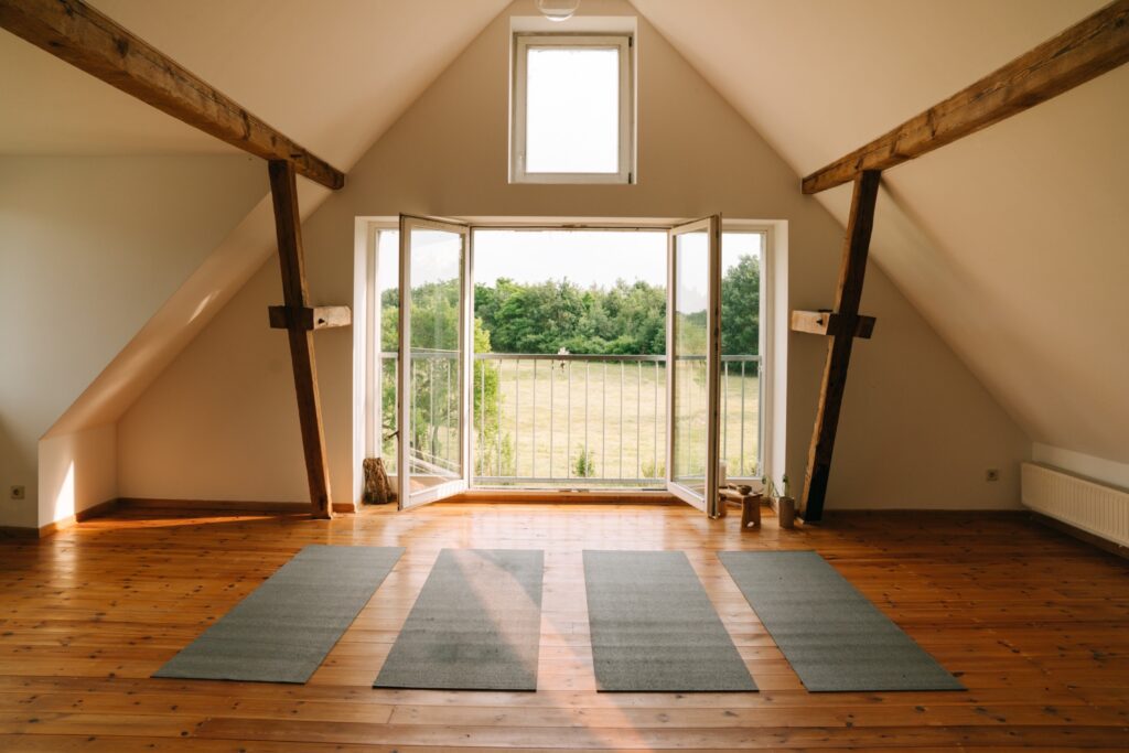 Raum mit großen offenen Fenstern und vier Yogamatten