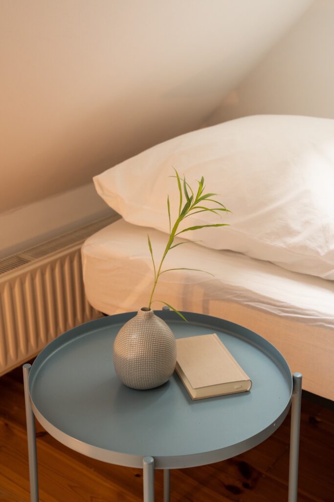 Schlafzimmer mit weißer Baumwollbettwäsche Bett mit weißer Baumwollbettwäsche und blauem Beistelltisch