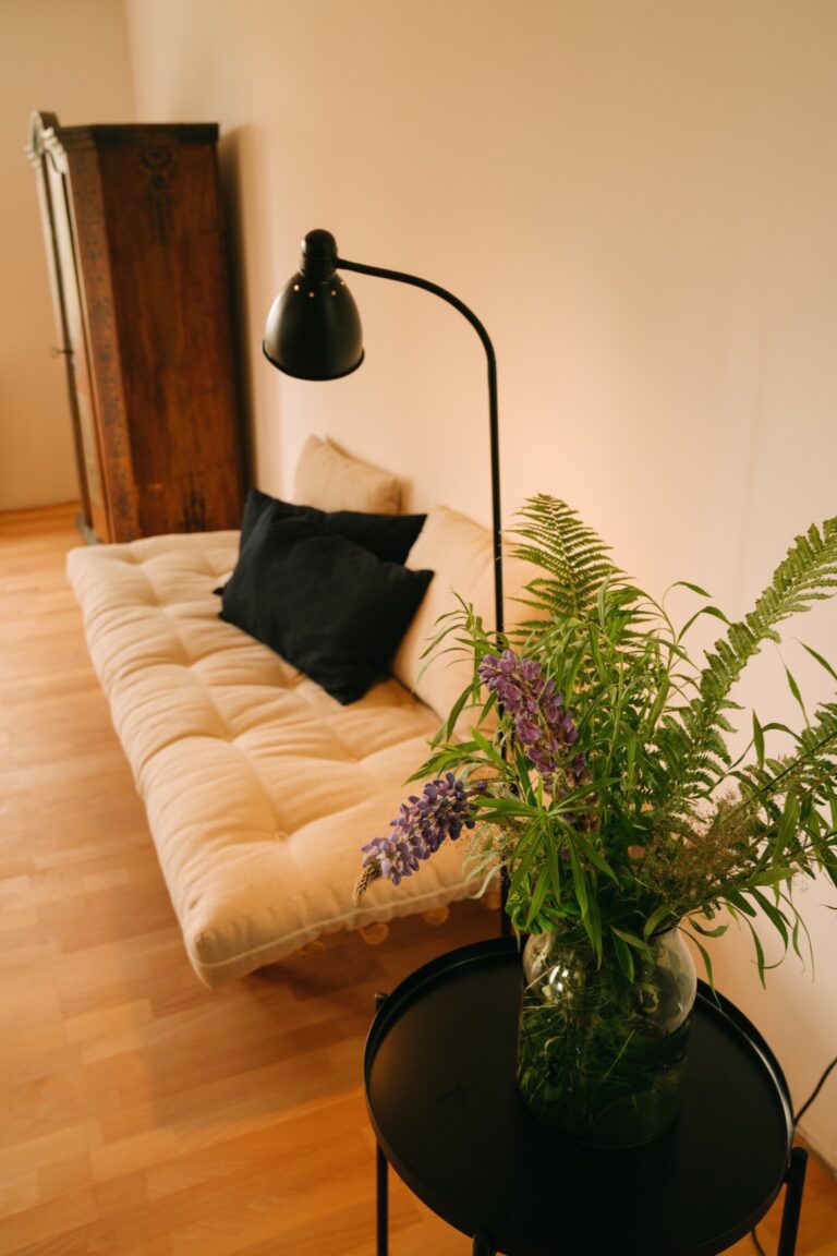 Helles Sofa mit schwarzer Leselampe und Beistelltisch mit Blumen