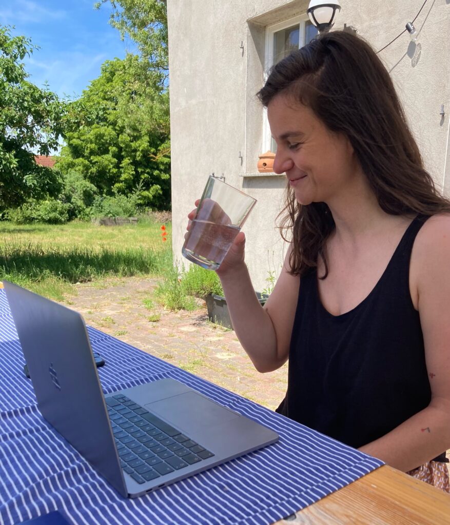 Frau sitzt draußen an einem Tisch am Laptop